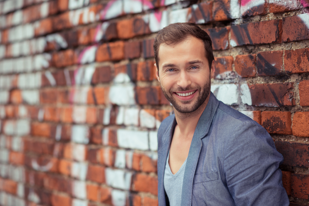 Close up Happy Handsome Man in Trendy Fashion Leaning on Old Brick Wall While Looking at the Camera.