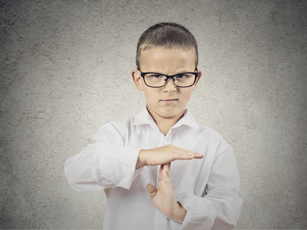 Closeup portrait serious young man, child, making, showing time out gesture with hands, isolated grey wall background. Negative human emotions, facial expressions, feeling, signs symbol body language